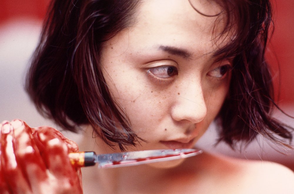 Auf diesem Filmstill h&auml;lt eine Frau ein blutverschmiertes Messer an ihren Mund. | © Stance Company